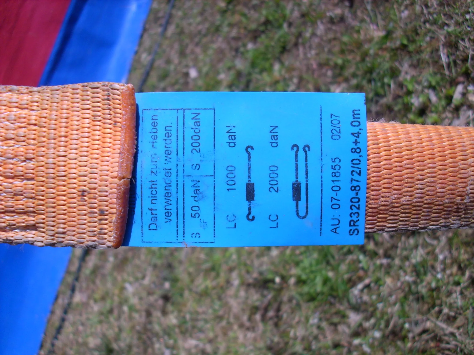 Blauw etiket van een spanband met LC- en SHF-waarden volgens EN 12195-2